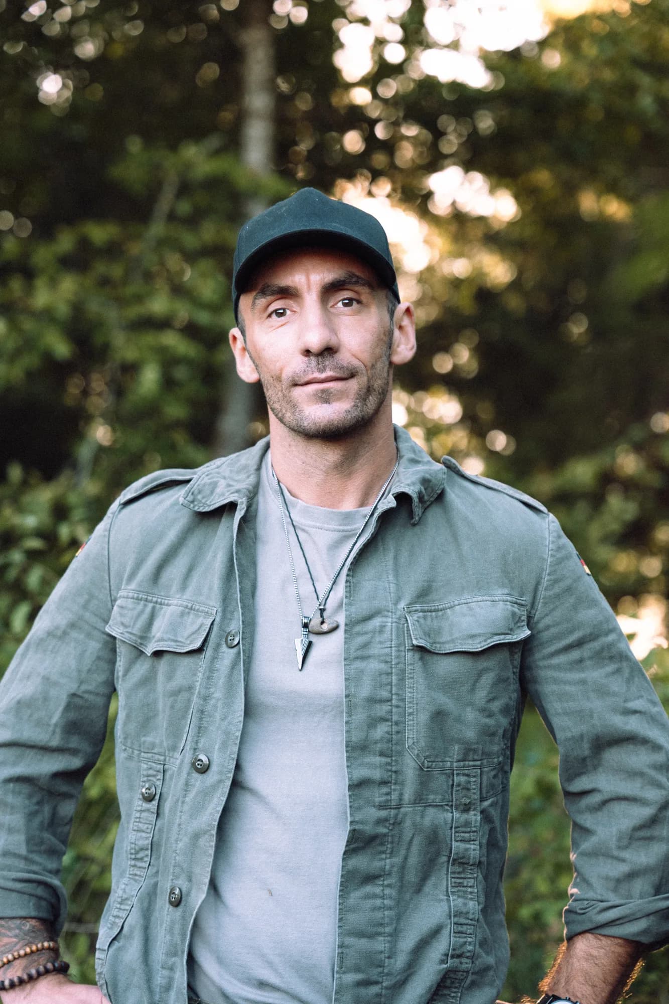 Adrian mit grüner Jacke und Kappe im Wald
